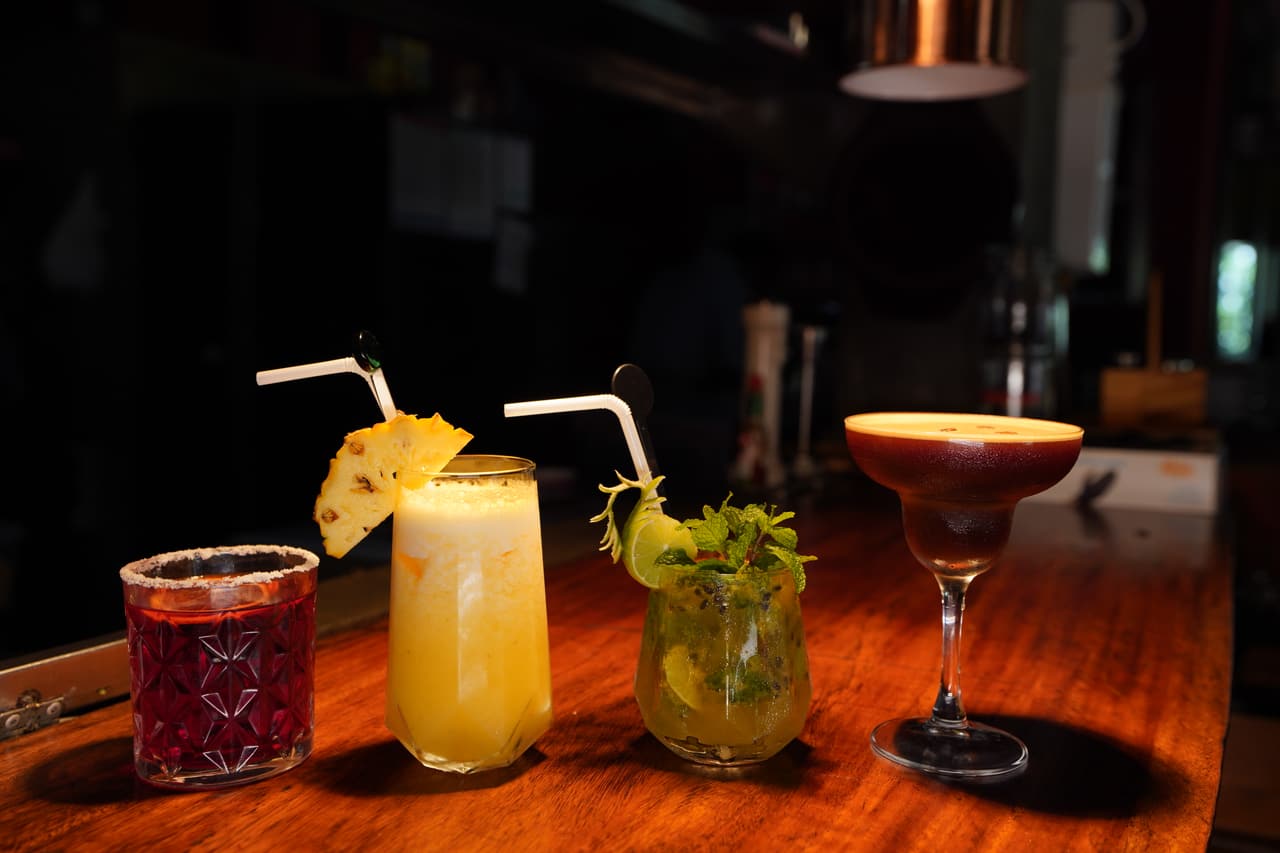 Four cocktails on the bar at AK Ristoro, Ella — a red tumbler with a sugared rim, a pineapple highball, a mojito and an espresso martini