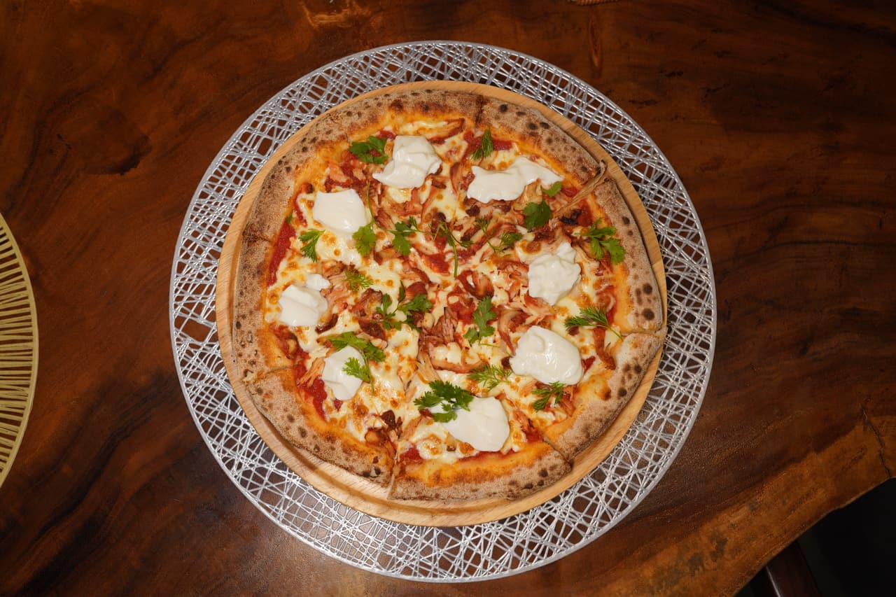 Tandoori chicken pizza at AK Ristoro, Ella — dollops of buffalo curd and fresh coriander on a wire charger