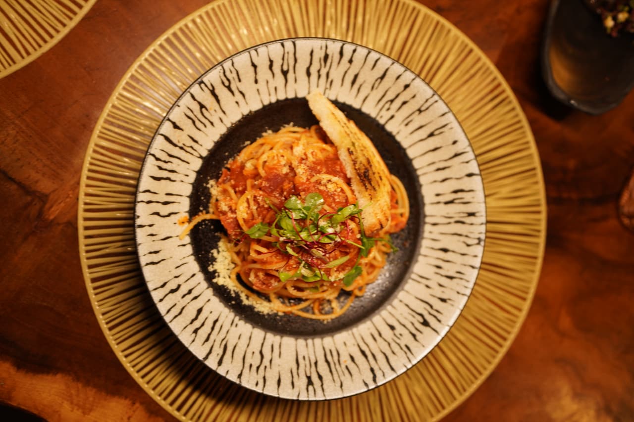 Tomato spaghetti at AK Ristoro, Ella — Parmesan, herbs and garlic bread in a black-and-white bowl