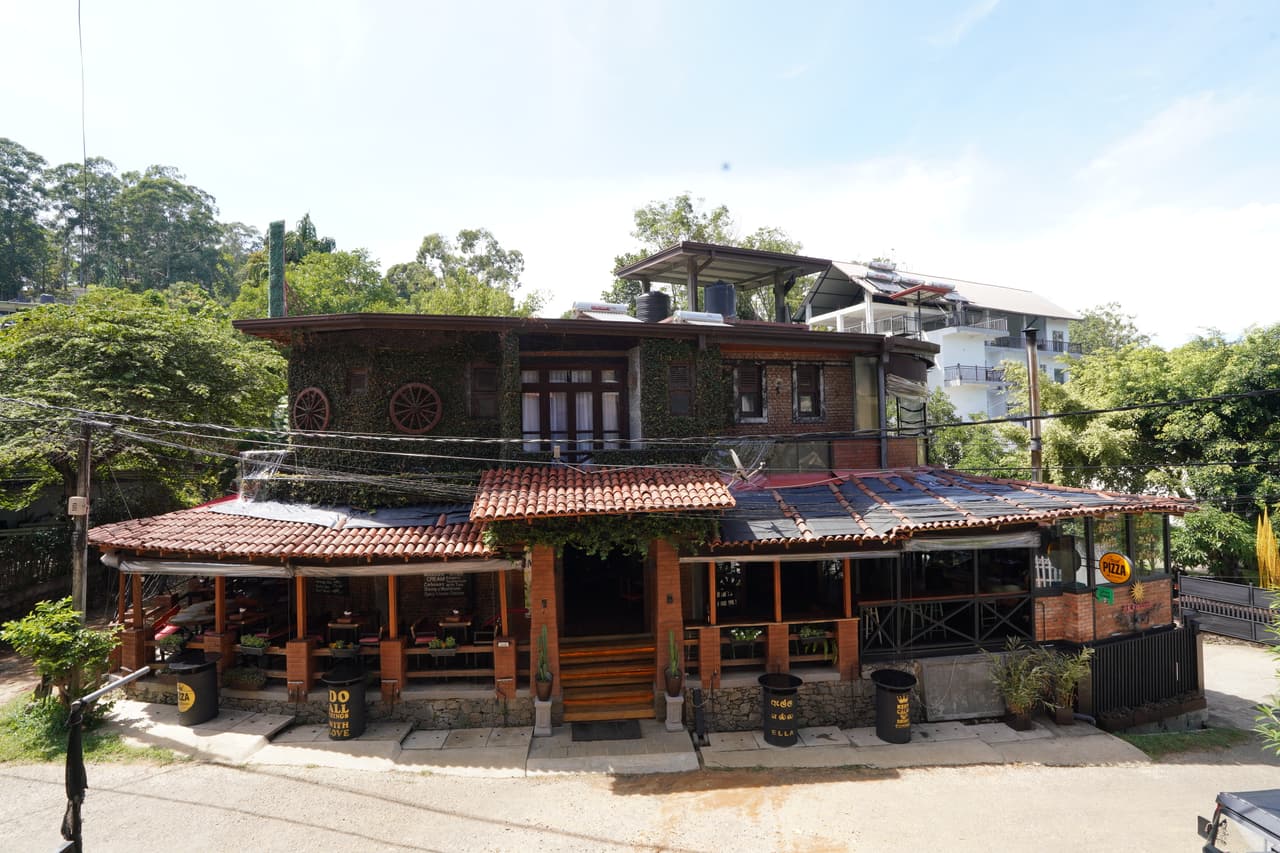 AK Ristoro on Passara Road, Ella, on a clear morning — the timber restaurant with its tiled roofs and wagon wheels