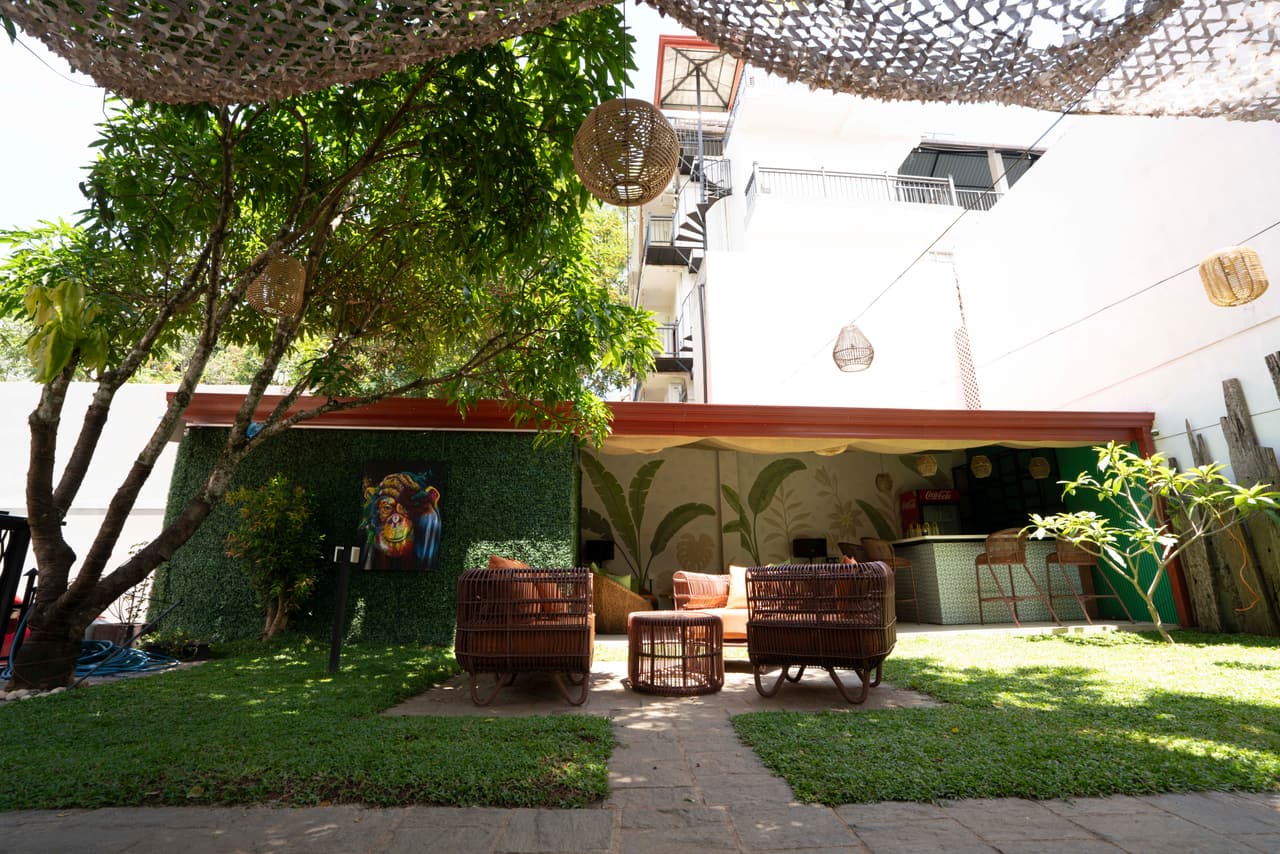 The garden at AK Ristoro, Ella, by day — wicker seats on the lawn under a shade net and woven lanterns